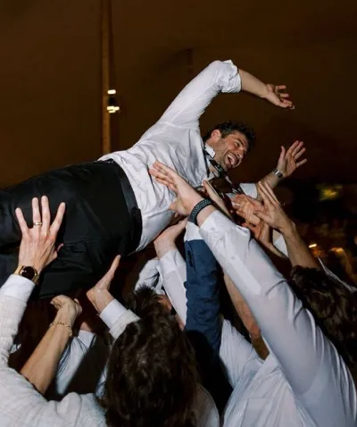 Wedding guests lifting a celebrating guest into the air, every hand free